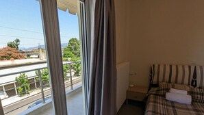 A bedroom with a bed, a radiator, and a view of a balcony with a railing. - Samaras Apartments Le Grand (Kamena Vourla)