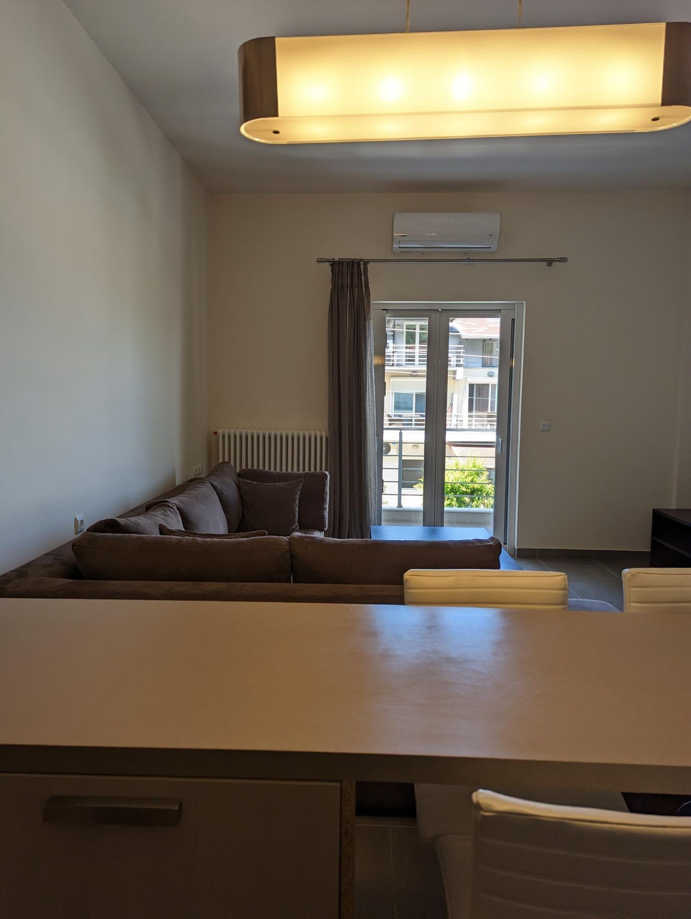 A modern living room with a sofa, a dining table, and a view of the outside.