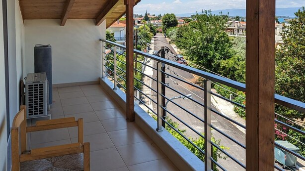A balcony with a wooden ceiling, a chair, and an air conditioning unit. - Samaras Apartments - Sea View Attic (Kamena Vourla)