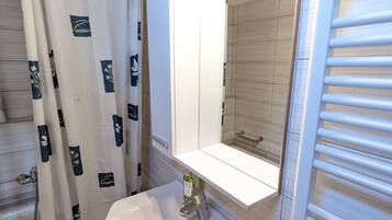 A bathroom with a white sink, a mirror, and a shower curtain with floral patterns.