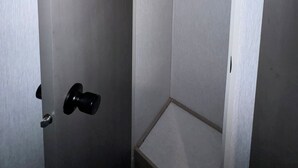 Een kleine, afgesloten douche ruimte met een houten deur en een metalen handdoekhouder.