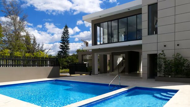 Una moderna casa a due piani con piscina e un patio coperto.