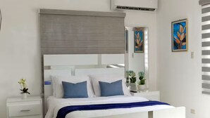 Una camera da letto moderna con un letto grande, comodini bianchi, uno specchio e due quadri appesi al muro.