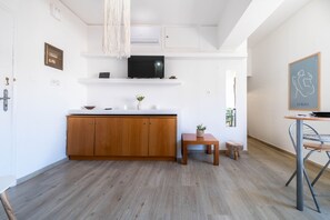 Una cocina moderna con armarios de madera, un televisor y una pequeña mesa con una planta.