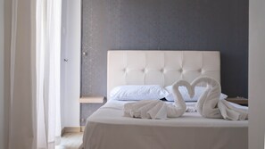 Una habitación de hotel con una cama grande, cabecera y pared con diseño geométrico.