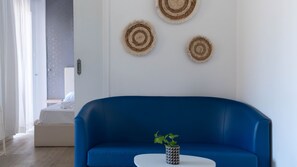 Una sala de estar moderna con un sofá azul, una mesita blanca y una planta en maceta.