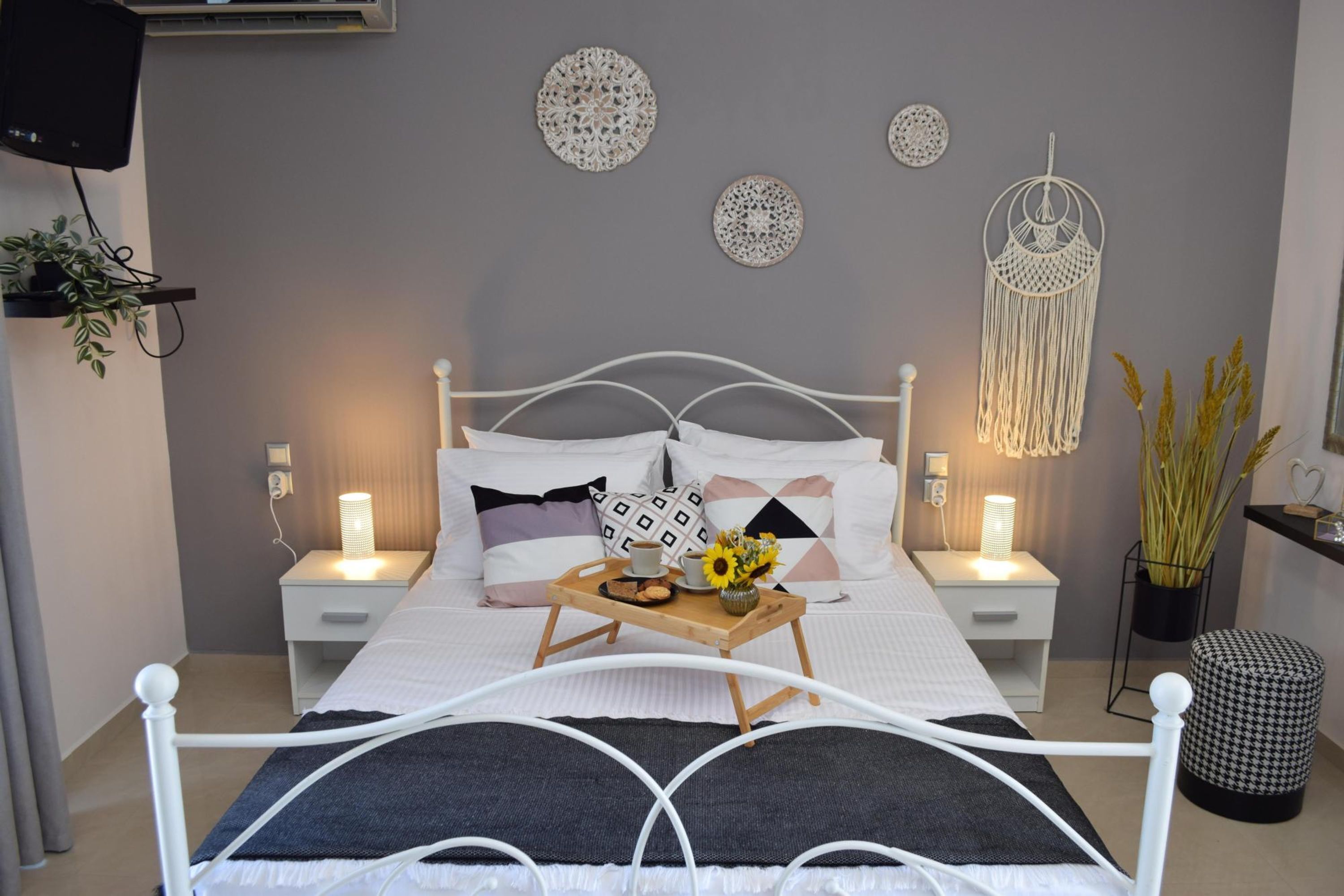Quarto bem arrumado com uma cama, mesas de cabeceira, arte decorativa na parede e um pendente de macramé.