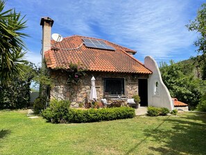 Ein Haus aus Stein mit Ziegeldach, Solaranlage und Garten.