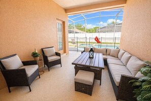 Un patio iluminado por el sol con mobiliario de mimbre, una piscina y vistas despejadas al exterior.