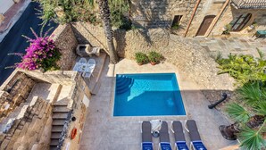 A rooftop pool with a stone deck, surrounded by potted plants and a stone wall. - Kikka - Xaghra Holiday Home (Ix-Xagħra)