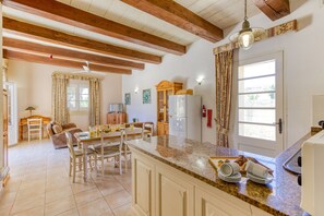 A spacious kitchen with a granite countertop, wooden beams, and a dining area with a table and chairs.