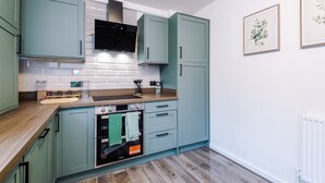 Una cocina moderna con armarios color turquesa, una campana de acero inoxidable, un horno empotrado y una encimera de madera.