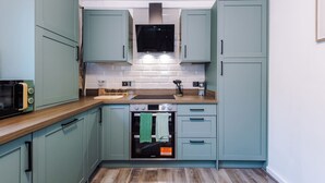 Una cocina compacta con armarios azul turquesa, horno empotrado y microondas.