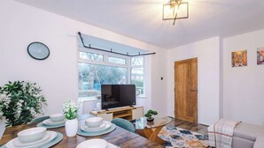 Una sala de estar moderna con comedor, televisor y un amplio ventanal.