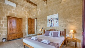 A bedroom with a bed, wooden wardrobe, bedside tables, and a painting on the wall. - Gharilma IV – Santa Lucija Holiday Home (Ta' Kerċem)