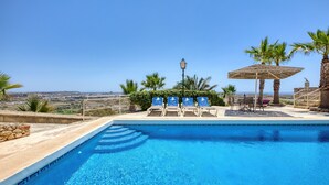 A swimming pool with lounge chairs and a view of the landscape. - Gharilma IV – Santa Lucija Holiday Home (Ta' Kerċem)