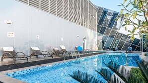 Un espace piscine moderne avec des chaises longues et un bâtiment en verre en arrière-plan.
