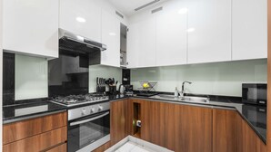Une cuisine moderne avec des meubles blancs, un plan de travail noir et un four encastré.