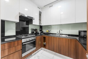 A modern kitchen with white cabinetry, a black countertop, and a built-in oven. - Stayshort - Modern 1BR in Business Bay for 2 (Dubai)