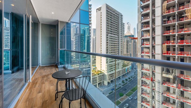 Un balcon avec une table et des chaises, offrant une vue sur le paysage urbain et ses grands immeubles.