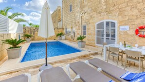 A pool area with lounge chairs, a table set for dining, and a lifebuoy on the wall. - Girardu - Victoria Holiday Home (Victoria)