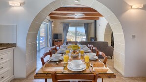 Un coin repas avec une table mise pour le petit-déjeuner, une arche en pierre et une vue sur l’extérieur.