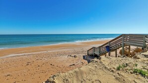 A beach with a wooden staircase leading down to the shore, clear blue sky, and calm sea. - Beach Escape with Never Ending Views and Direct Beach Access (Ormond Beach)