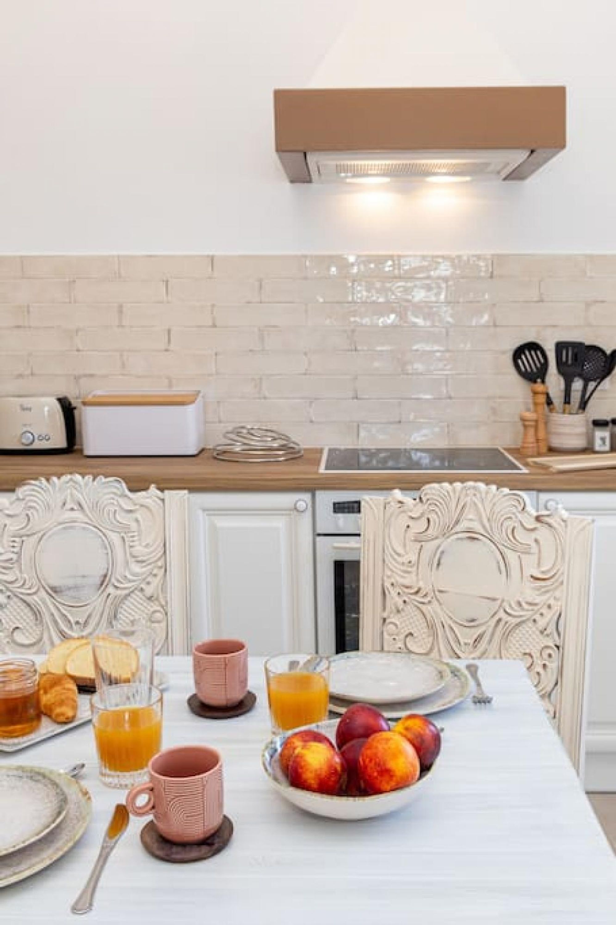 A breakfast setup with a toaster, a kettle, and a fruit bowl on a table.