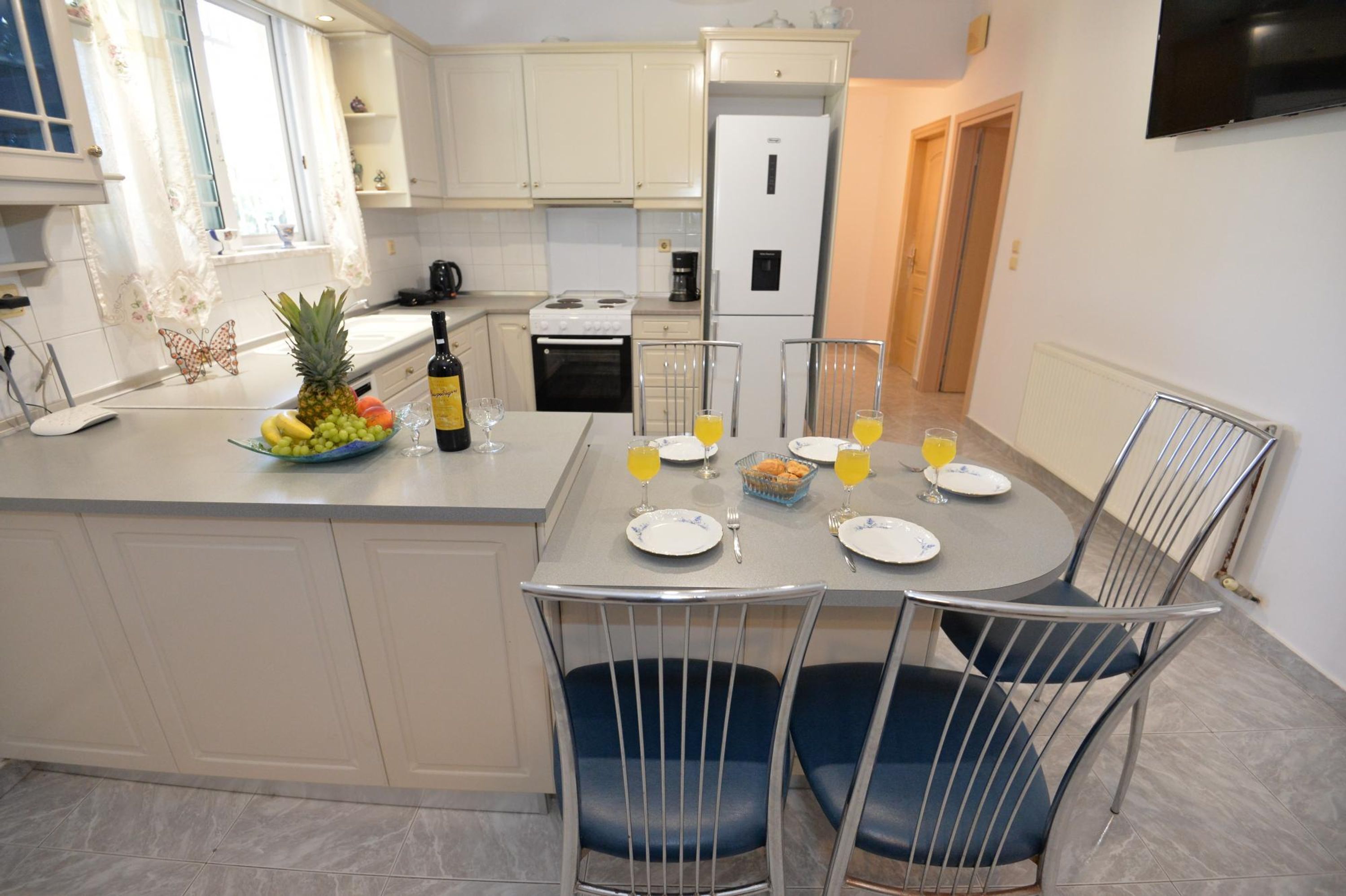 Una cocina moderna con armarios blancos, una mesa de comedor con sillas y un refrigerador.