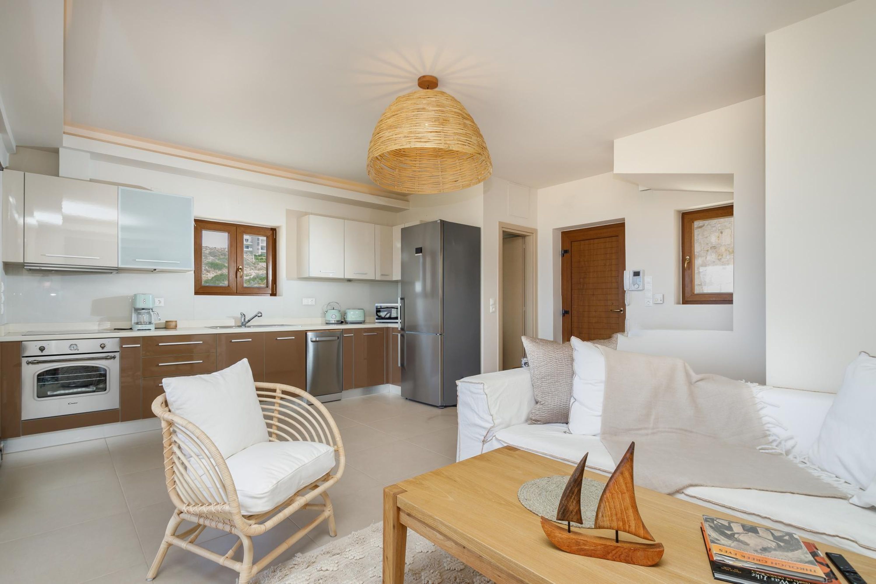 A modern kitchen with white cabinets, stainless steel appliances, and a wicker chair.