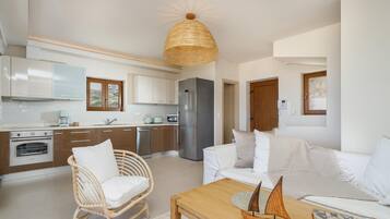 A modern kitchen with white cabinets, stainless steel appliances, and a wicker chair.