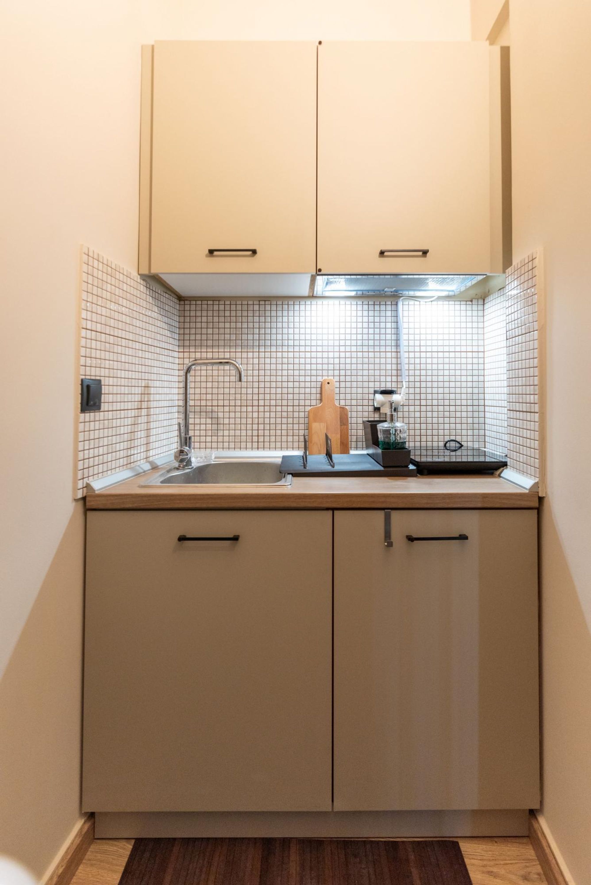 Una cocina compacta con un lavamanos, una encimera y una tabla de cortar de madera.