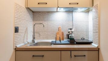 Una cocina compacta con un lavamanos, una encimera y una tabla de cortar de madera.