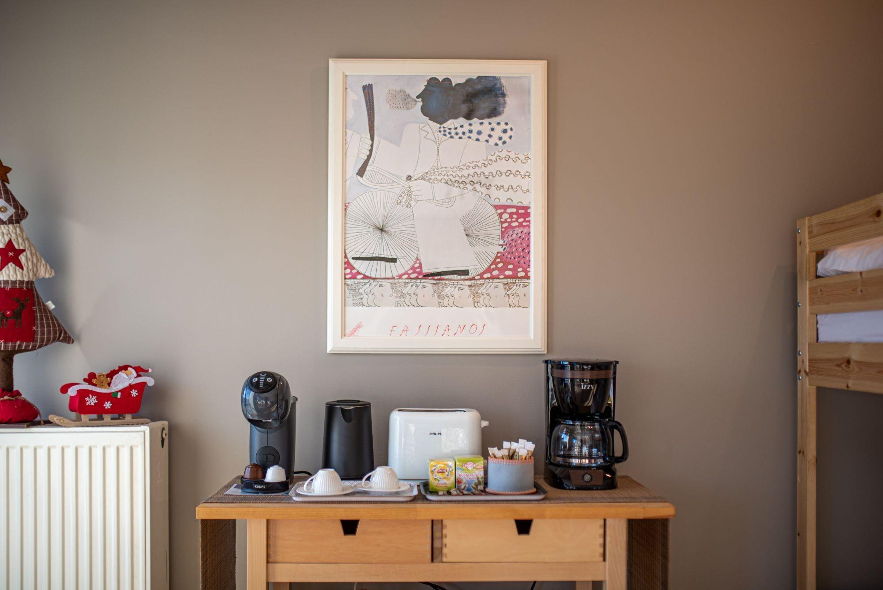 Una kitchenette con cafetera, tostadora y hervidor sobre una mesa de madera.