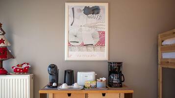 Una kitchenette con cafetera, tostadora y hervidor sobre una mesa de madera.