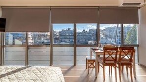 Une chambre avec une grande fenêtre, un lit, un bureau et une chaise.