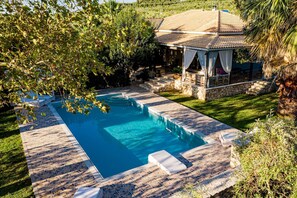 A swimming pool with a stone deck, a gazebo, and a lush garden. - Eleonas Private pool villa (Galaro)