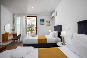 Ein Hotelzimmer mit zwei Betten, einem Schreibtisch mit Stuhl, einem Spiegel und einem Fenster mit Vorhängen.