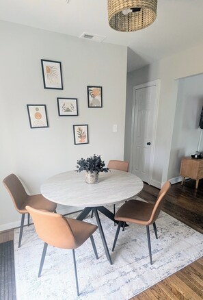 A dining area with a round table, four chairs, and a woven ceiling light. - Cozy 3 BdRm Cape Cottage in Green Park, RVA - 10 minutes 2 Downtown  (Richmond)