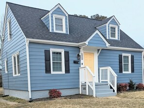 A two-story house with a gabled roof, a front porch with a white railing, and a front door. - Cozy 3 BdRm Cape Cottage in Green Park, RVA - 10 minutes 2 Downtown  (Richmond)