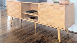 A wooden TV stand with a flat-screen TV mounted on the wall above it.