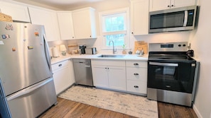 A modern kitchen with white cabinets, stainless steel appliances, a microwave, and a dishwasher. - Cozy 3 BdRm Cape Cottage in Green Park, RVA - 10 minutes 2 Downtown  (Richmond)