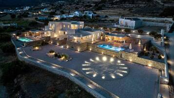 A modern hotel with a circular pool, outdoor seating, and a stone courtyard.