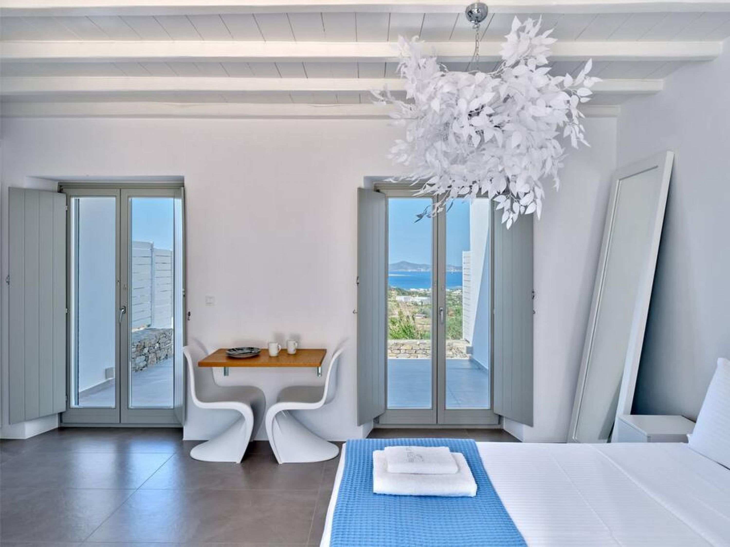 A modern hotel room with a balcony, a dining area, and a bed.