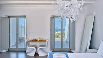 A modern hotel room with a balcony, a dining area, and a bed.