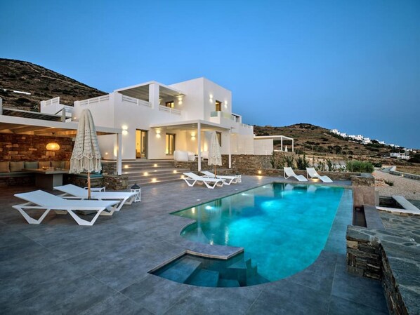 A modern villa with a swimming pool, outdoor seating, and a view of the surrounding landscape. - La Vitalite Luxury Villa Mer in Paros (Aliki)