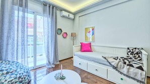 Un dormitorio moderno con sofá cama, una mesa redonda y vistas al exterior a través de un ventanal amplio.