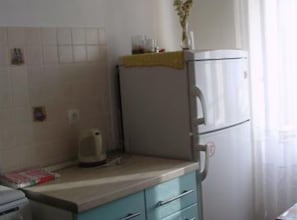 Eine Küche mit einem Kühlschrank, einem Wasserkocher und einem Schrank.