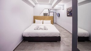 A modern hotel room with a large bed, a wooden headboard, and a view of the hallway and staircase. - Exclusive New Modern Apartment at Syntagma Square (Athina)