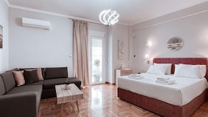 Moderni hotellihuone, jossa on suuri sänky, sohva, pieni pöytä ja kattovalaisin.